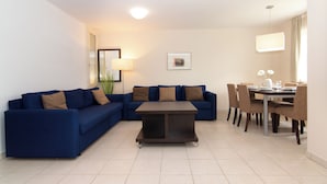 Una sala de estar moderna con un sofá azul, una mesa de centro y un comedor con sillas y una mesa.
