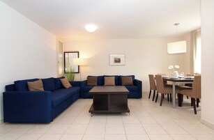 Una sala de estar moderna con un sofá azul, una mesa de centro y un comedor con sillas y una mesa.