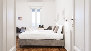 A bedroom with a bed, a desk, a chair, and a window.