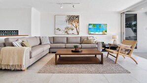 Una sala moderna con un sofá modular, una mesa de centro y un sillón de mimbre.
