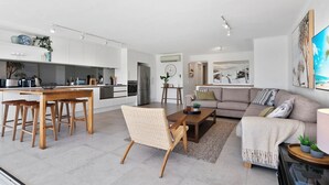 Una sala de estar moderna con sofá, mesa de centro y comedor con sillas y mesa de madera.