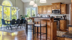 Una cocina amplia con armarios de madera, una isla grande con taburetes de bar e iluminación colgante.