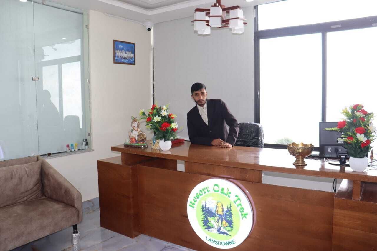 Un mostrador de recepción en un hotel, con un logotipo, un sofá y una araña.
