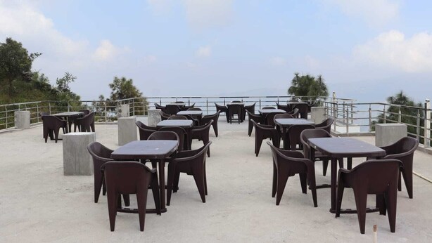 Une terrasse extérieure dotée de plusieurs tables et chaises, d’un sol en béton et d’une rambarde.