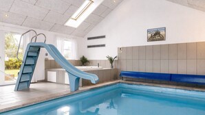 A swimming pool with a blue slide, a sunroof, and a view of the outdoors. - 5 Star Holiday Home in Idestrup (Idestrup)