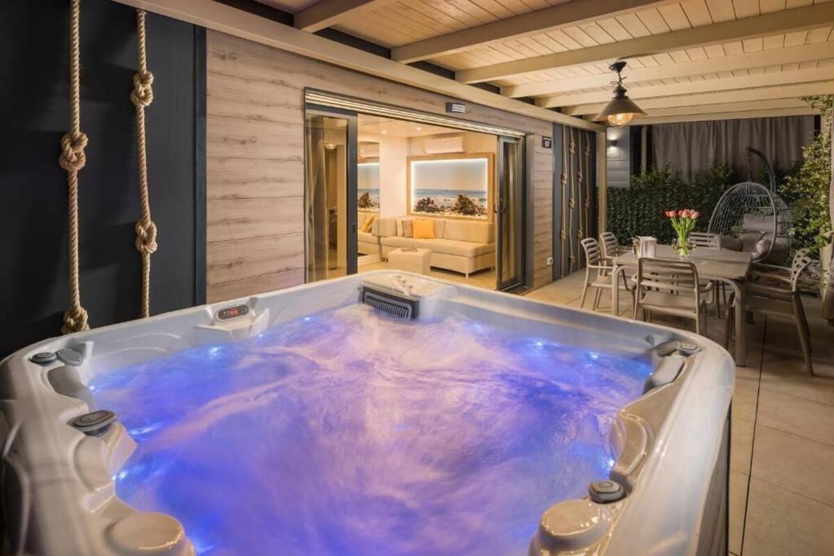 A modern indoor hot tub with a view of a living area, including a sofa and dining table.