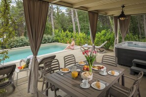 A covered outdoor dining area with a pool and hot tub in the background. - Premium Camping Homes Santa Marina (Tar-Vabriga)