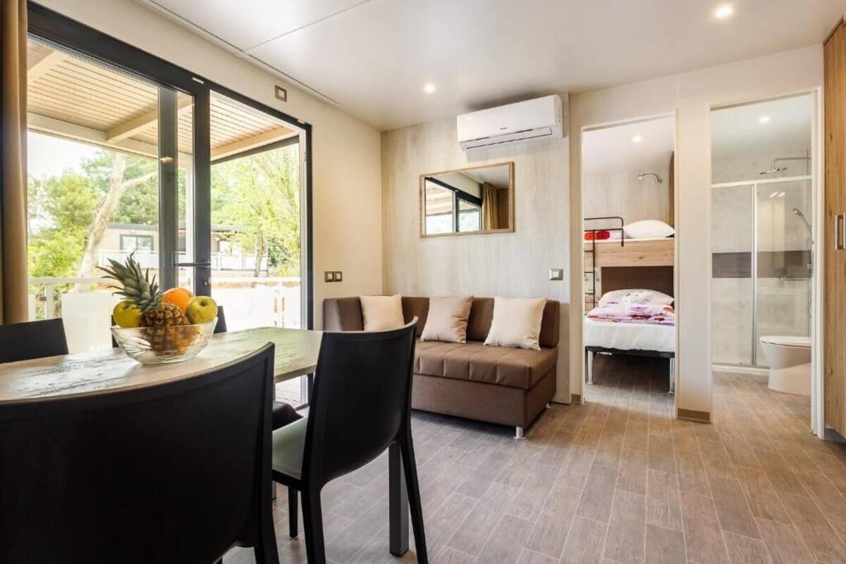 A modern room with a dining area, a sofa, a bed, and a bathroom.
