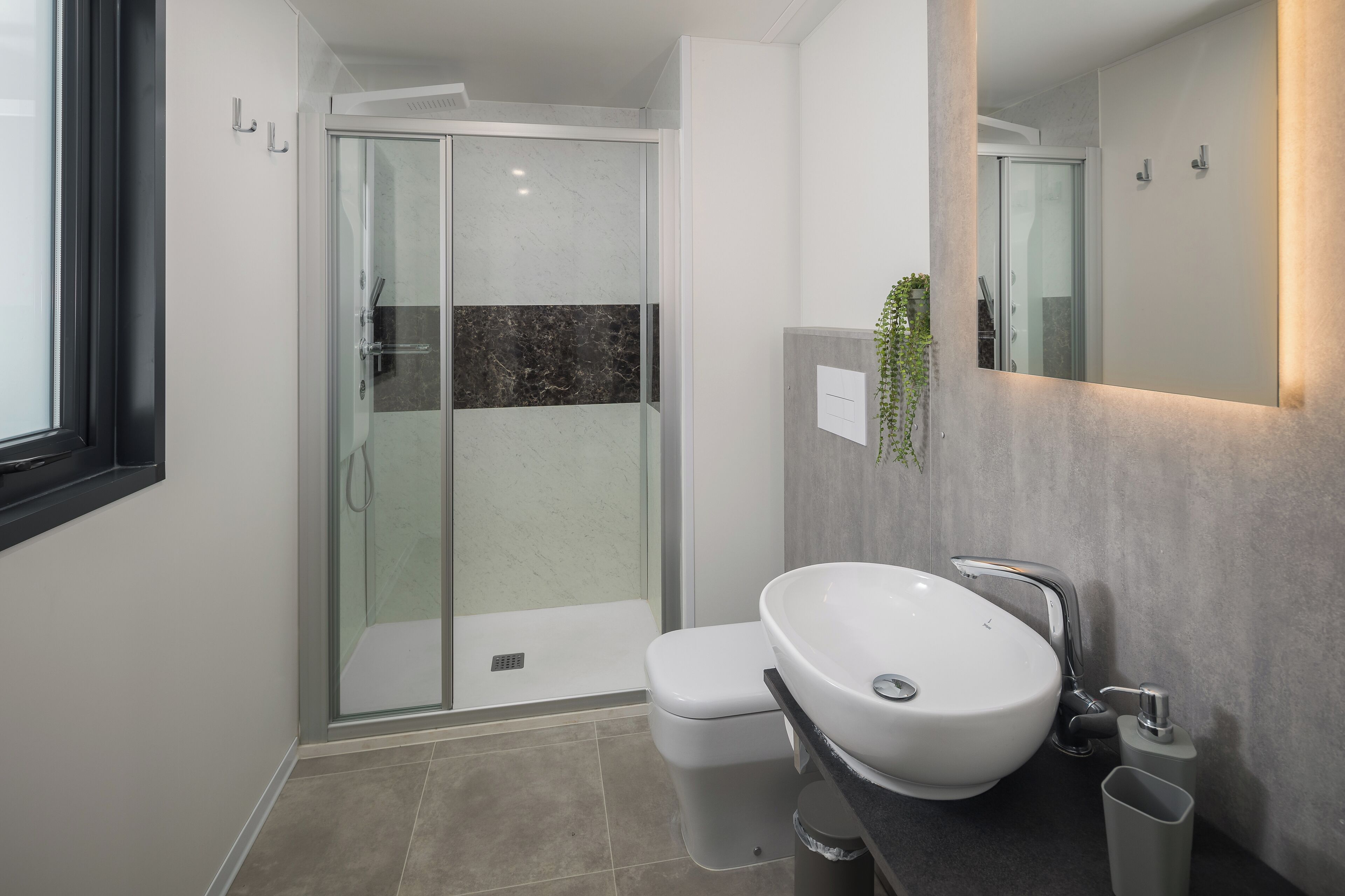 A modern bathroom with a glass-enclosed shower, a white sink, and a mirror.