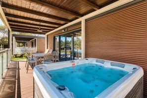 A hot tub on a wooden deck with a covered patio, outdoor furniture, and a view of the surrounding landscape. - Premium Camping Homes Santa Marina (Tar-Vabriga)