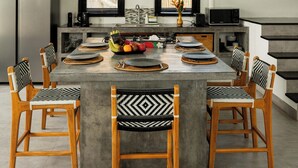 A modern kitchen with a central island, wooden chairs, and a built-in refrigerator. - Villa Sakayana (Canggu)