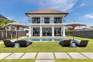 A two-story house with a swimming pool, lounge chairs, and umbrellas. - Villa Sakayana (Canggu)