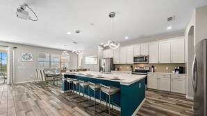 Una cocina moderna con una isla grande, armarios blancos y suelo de madera.