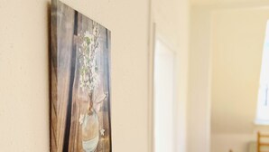 Ein Essbereich mit einem Holztisch und Stühlen, einer weißen Wand mit einem gerahmten Kunstwerk sowie einer Tür zu einem anderen Raum.