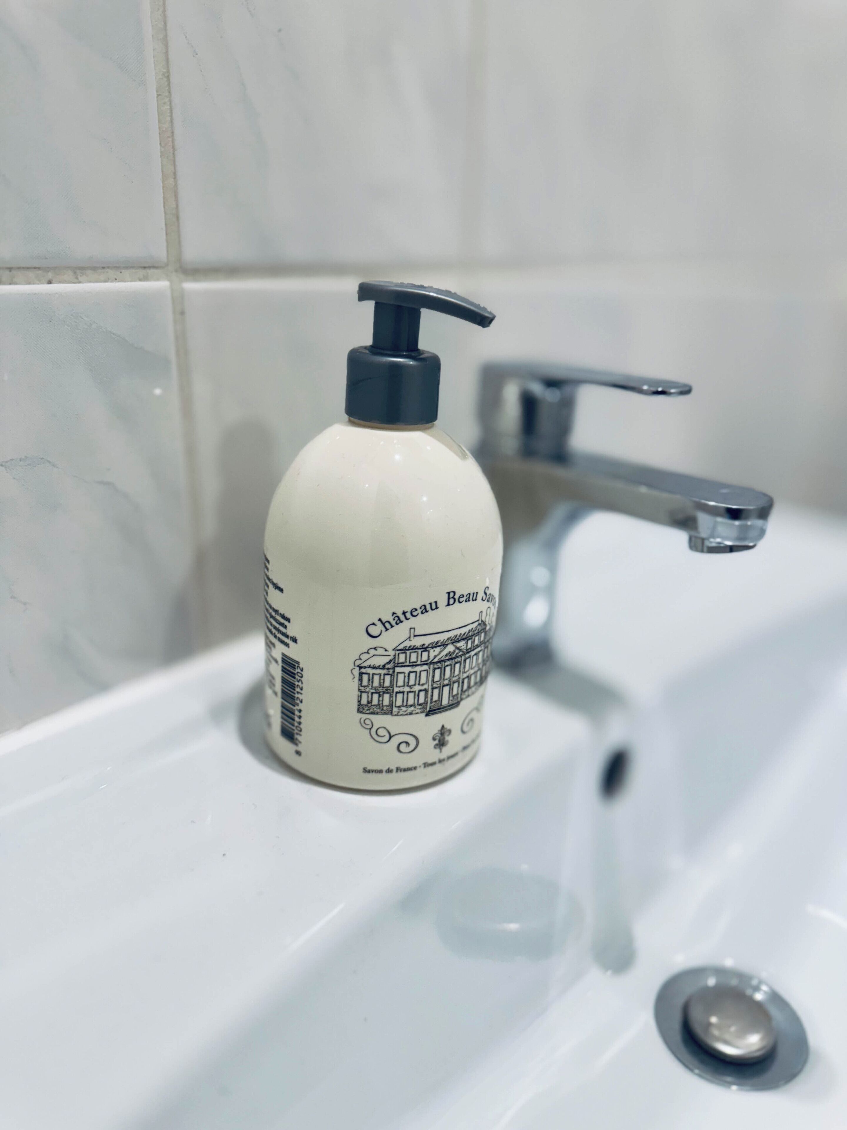 A bottle of Chateau Beau Sam soap on a bathroom sink.