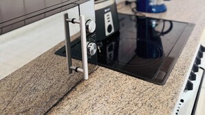 Eine Küche mit einem schwarzen Induktionskochfeld, einer Kaffeemaschine und einer Arbeitsplatte aus Granit.