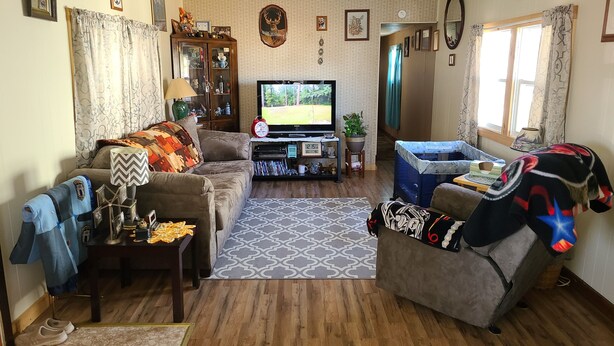 A cozy living room with a sofa, a television, a coffee table, and a baby playpen.