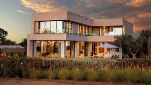 A modern two-story house with large windows, a covered outdoor seating area, and a well-maintained garden. - Villa Blanchette  (Marrakech)