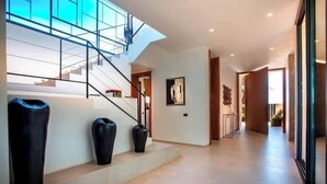 A modern interior with a staircase, large vases, and a hallway leading to a door. - Villa Blanchette  (Marrakech)