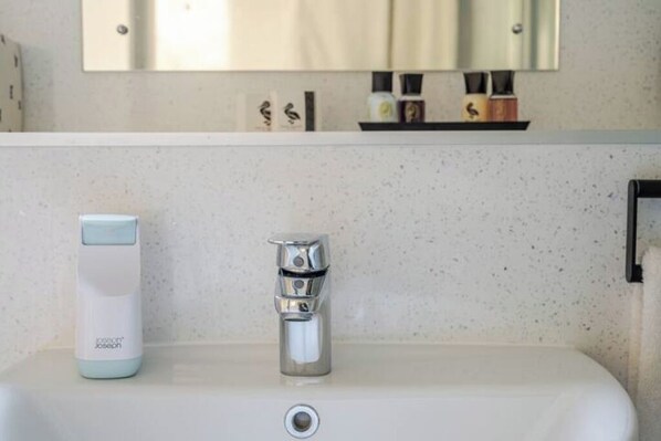 A bathroom with a white sink, a chrome faucet, and a soap dispenser. - Riverside Garden Apartment with lovely River Tay views and parking
(Perth)
