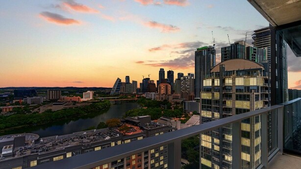 Um edifício alto com vista para o horizonte urbano e um rio.
