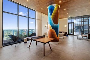 A spacious room with large windows, a central table, and a colorful cylindrical column.