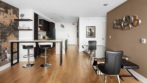 Cozinha moderna com área de bar, mesa de jantar com cadeiras e vista para a paisagem urbana pela janela.