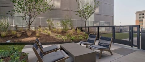 An outdoor seating area with a table and chairs, surrounded by a garden with various plants and trees.