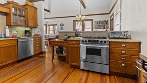 A kitchen with wooden cabinets, a stainless steel dishwasher, a gas stove, and a microwave. - !!Duck Pond Charming 3bed 2 bath house!! (Gainesville)