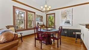 A dining area with a round table, wooden chairs, and a chandelier. There are large windows with wooden frames, and artwork on the walls. - !!Duck Pond Charming 3bed 2 bath house!! (Gainesville)