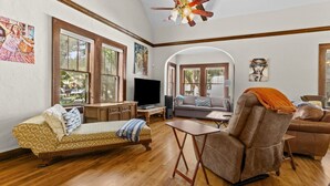 A spacious living room with a sofa, a recliner, a TV, and a wooden cabinet. - !!Duck Pond Charming 3bed 2 bath house!! (Gainesville)