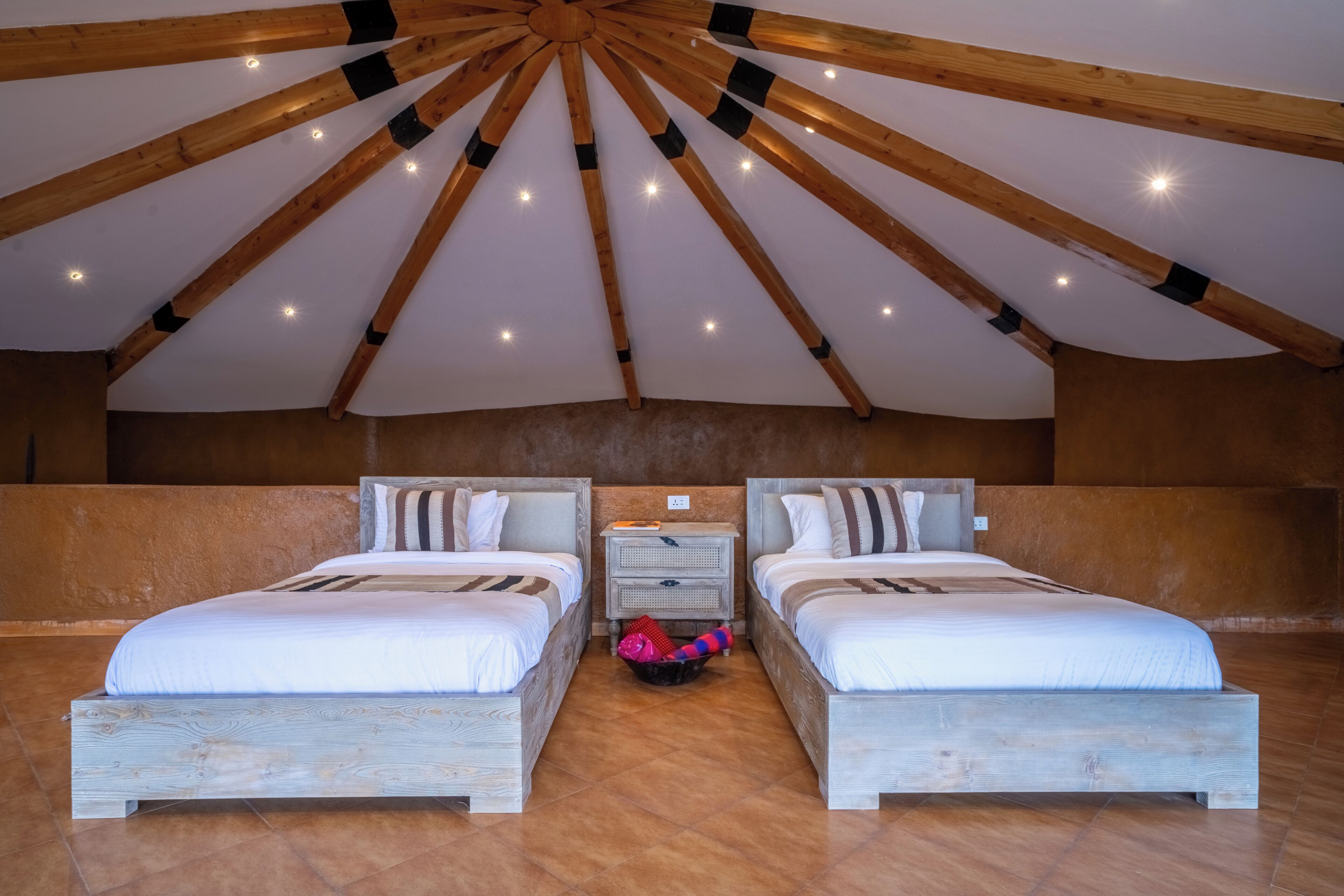 Een kamer met twee bedden, een houten plafond en een betegelde vloer.