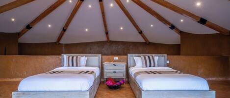Een kamer met twee bedden, een houten plafond en een betegelde vloer.