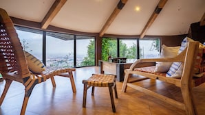 A spacious room with wooden furniture, large windows, and a view of the city.