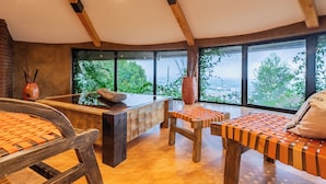 A modern interior with a wooden ceiling, large windows, a central island, and seating areas.