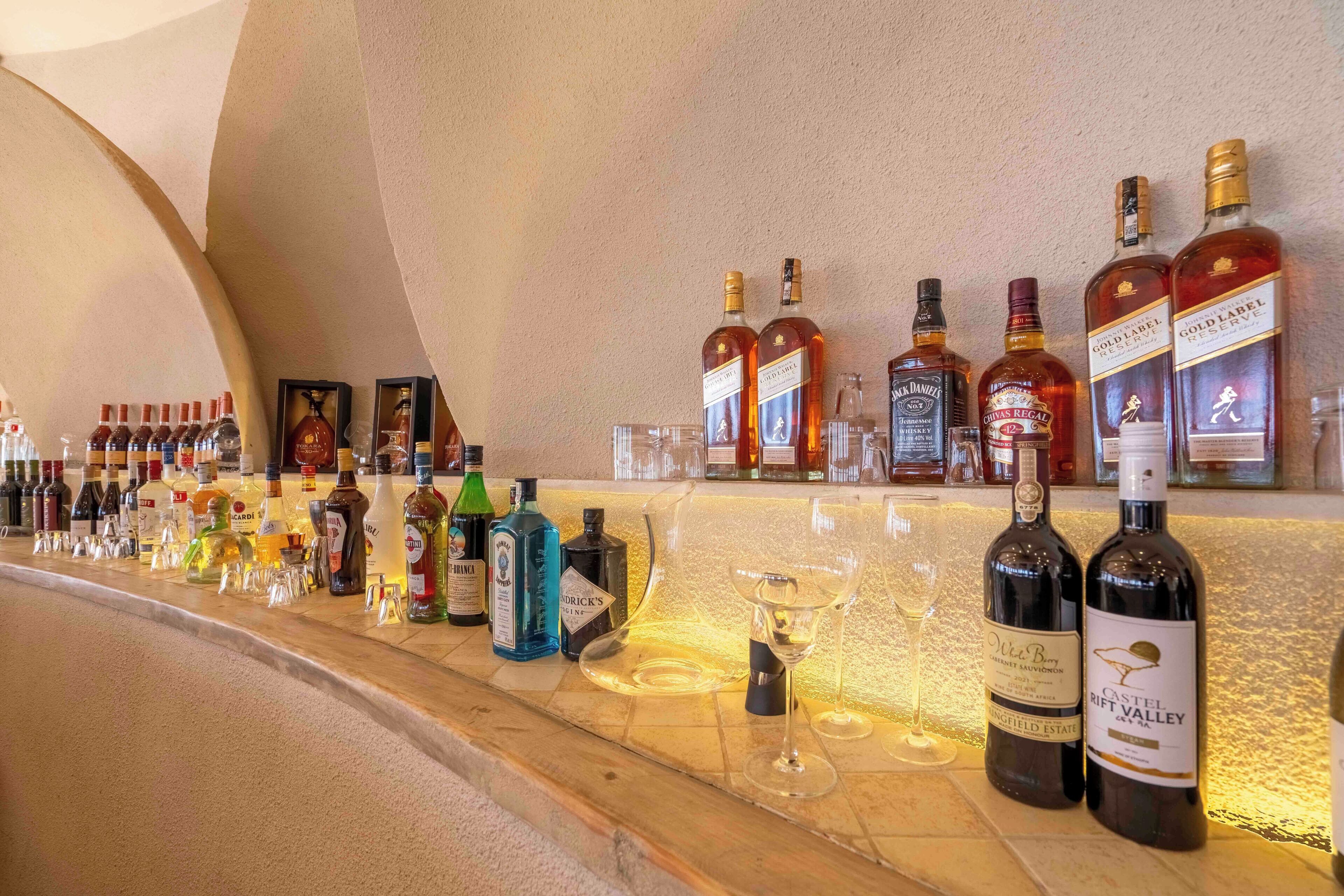 A bar area with various bottles of alcohol and glasses on the counter.