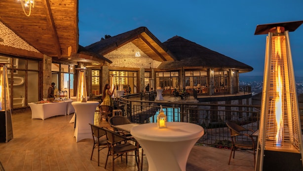 An indoor-outdoor dining area with a pool, wooden ceiling, and modern lighting fixtures.