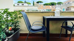 A balcony with a table and two chairs, overlooking a cityscape with buildings and trees. - Cozy house with balcony for couples 5 minutes from St. Peter's Basilica (Roma)