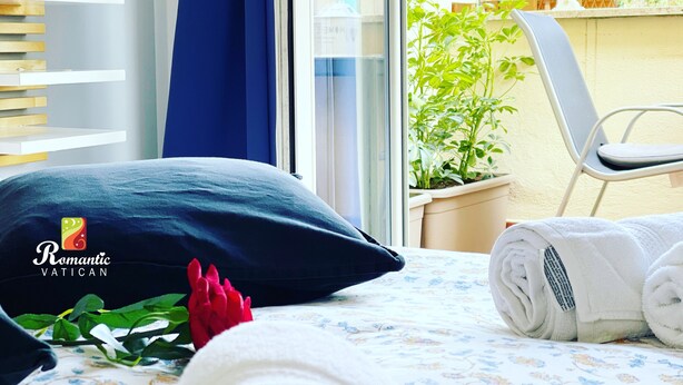 A hotel room with a bed, a window with a view of a building, a potted plant, and a chair. - Cozy house with balcony for couples 5 minutes from St. Peter's Basilica (Roma)