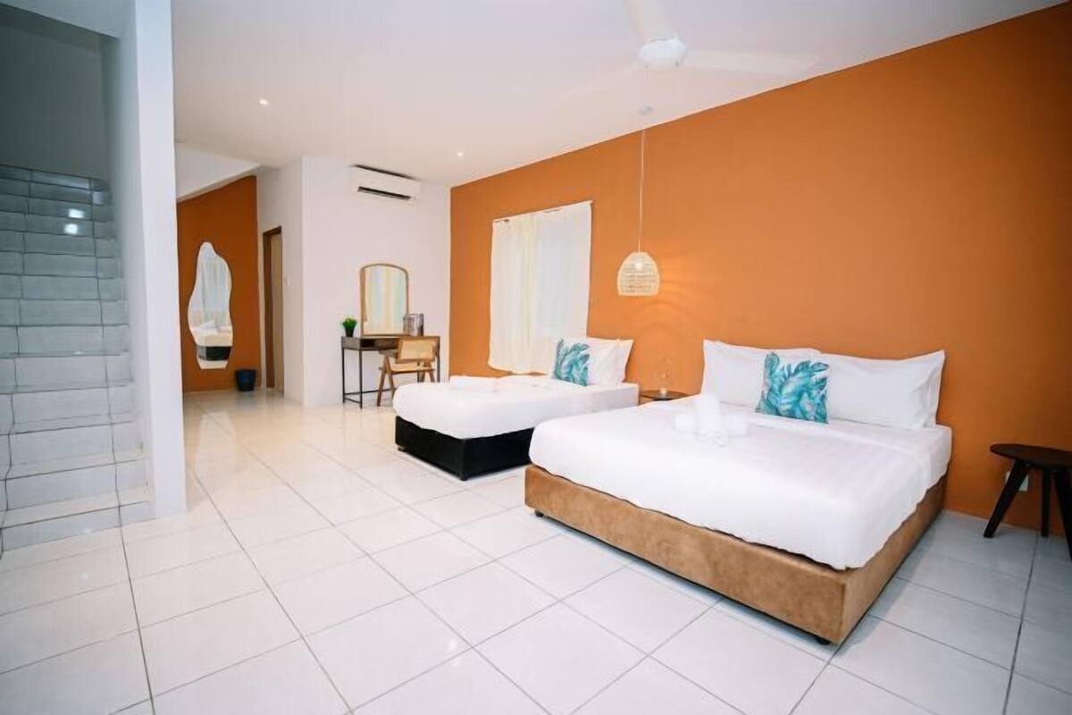 A hotel room with a large bed, a smaller bed, a desk, and a chair.