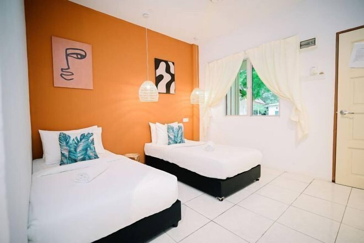A hotel room with two beds, white bedding, and a window with curtains.