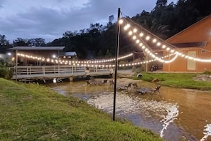 A riverside area with a wooden dock, chairs, and a building with string lights. - Lilla Rainforest Retreat @ Hulu Langat (Hulu Langat)