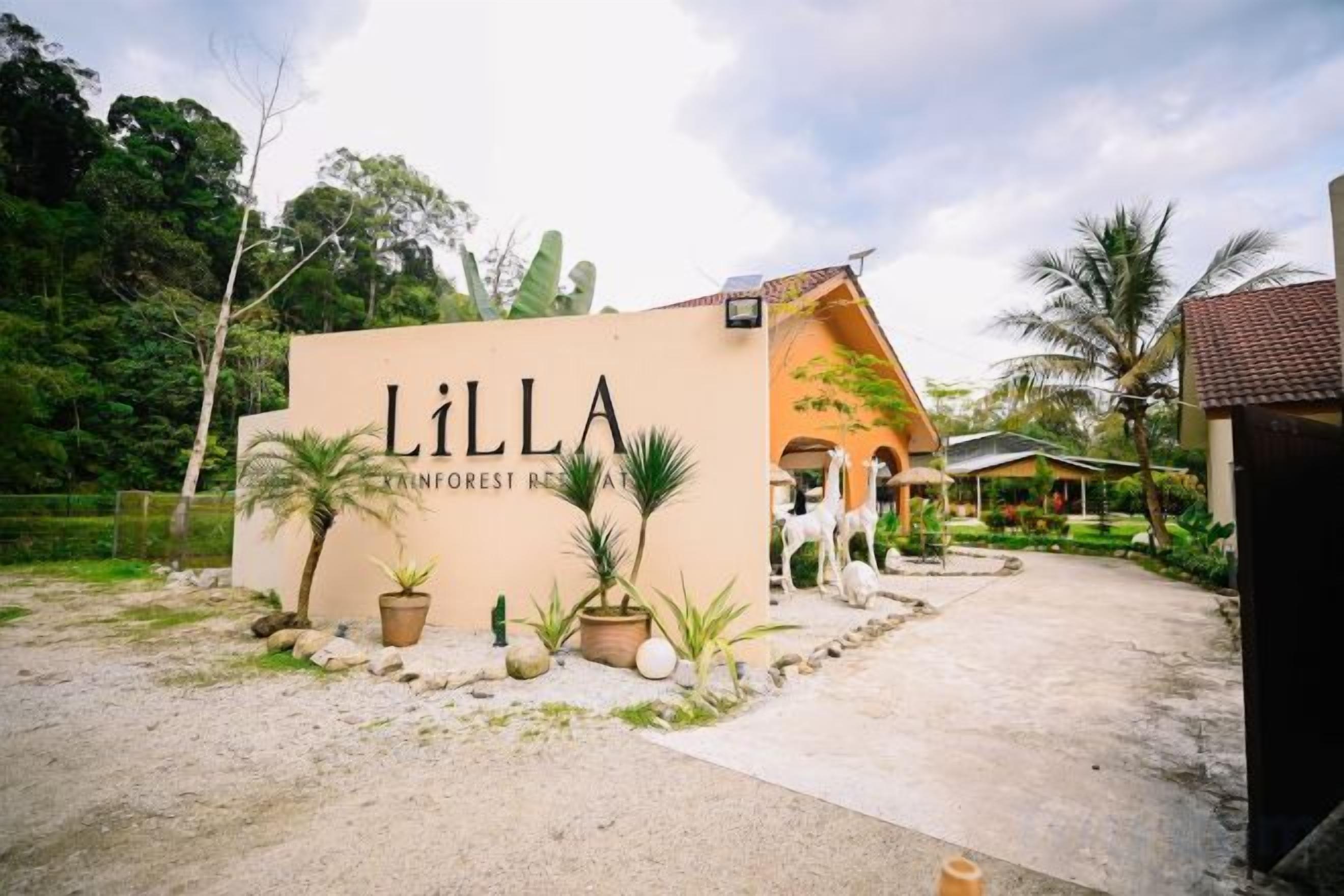 A building with a sign reading 'LILLA INNFOREST RESORT' surrounded by potted plants and palm trees.