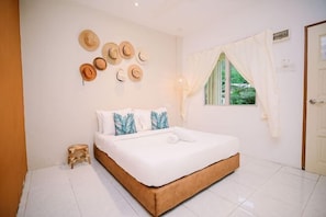 A bedroom with a bed, a small stool, a window with curtains, and a wall with hats. - Lilla Rainforest Retreat @ Hulu Langat (Hulu Langat)