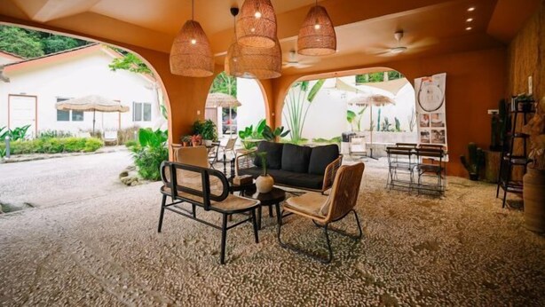 Un espace de détente intérieur, chaleureux, avec des meubles en osier, un canapé noir et une table basse.