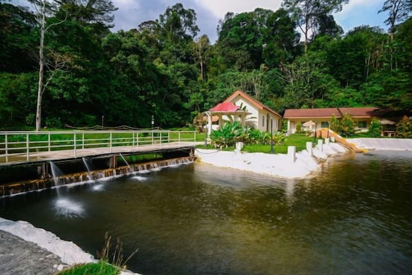 A house with a red roof near a calm water body, surrounded by lush greenery. - Lilla Rainforest Retreat @ Hulu Langat (Hulu Langat)