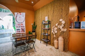 A reception area with a wooden bench, a wall-mounted shelf with decorative items, and a bulletin board. - Lilla Rainforest Retreat @ Hulu Langat (Hulu Langat)