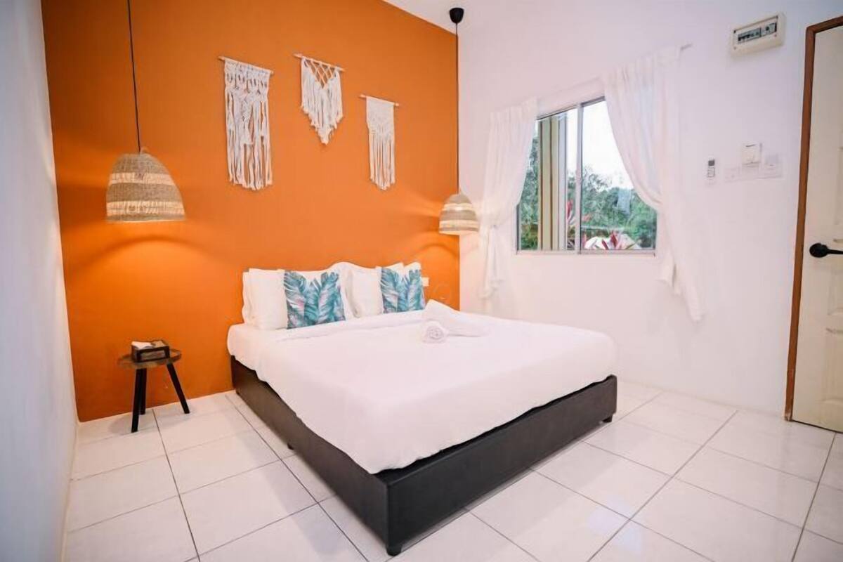 A bedroom with a bed, a window with curtains, and wall decorations.