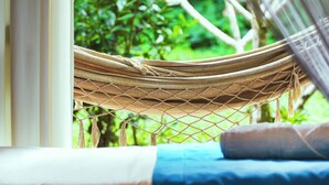 A hammock tied between two trees, with a bed and a window in the foreground. - VELINN Pousada Bali Itamambuca (Ubatuba)