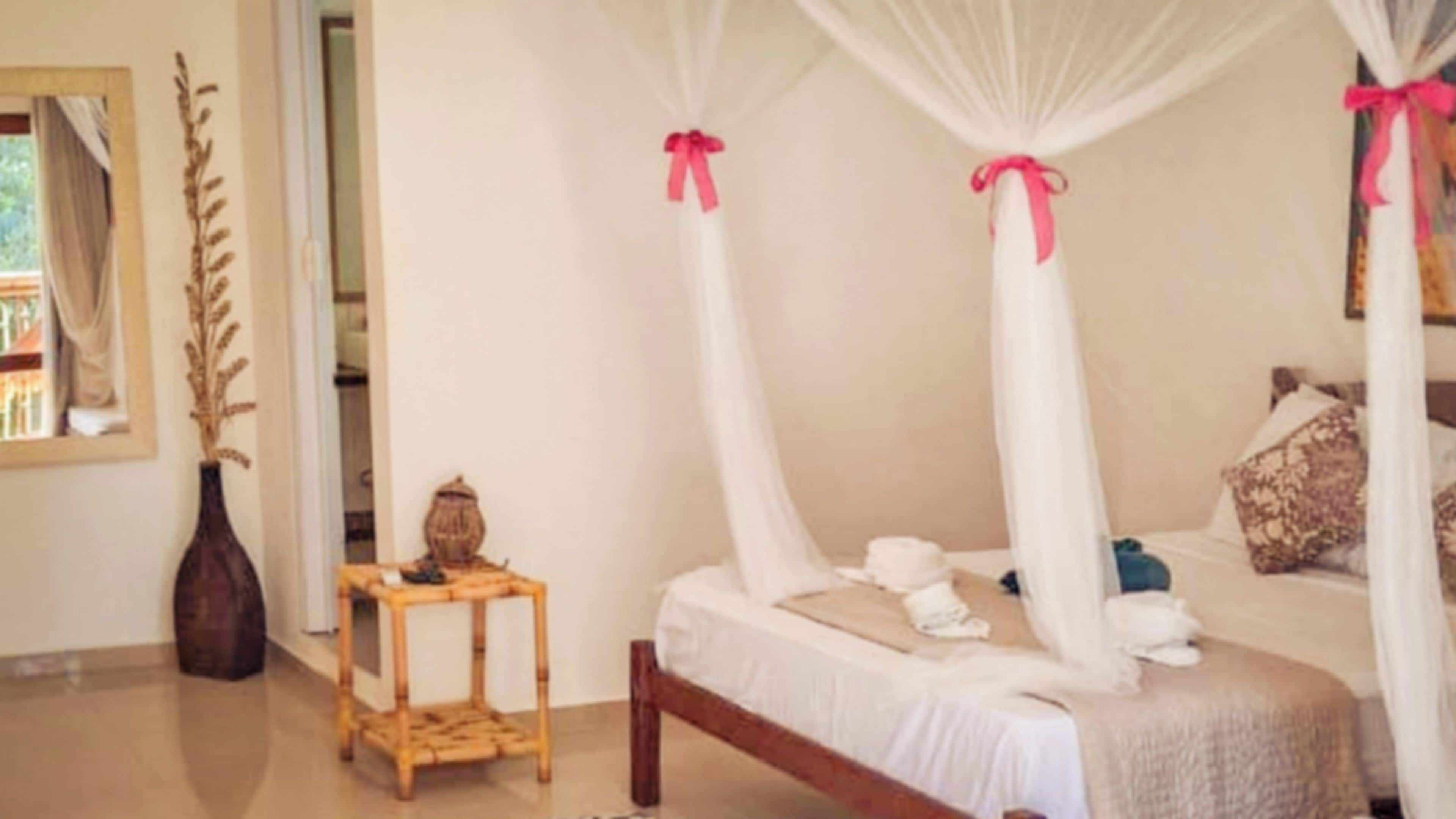 A bedroom with a four-poster bed, a bedside table, and a decorative vase.